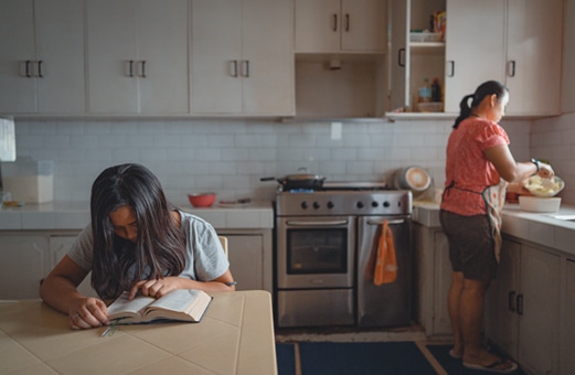 Girl reading with mom in kitchen