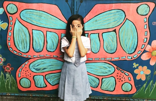 Cherry, a young girl, standing in front of a butterfly picture