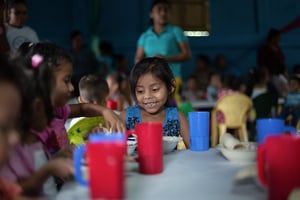 A little talks with friends at a lunch table set with plastic cus and bowls at a Hope Center in Nicaragua