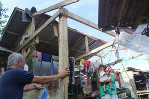 Child Champion speaks to a mother with a baby at the site of her damaged home.
