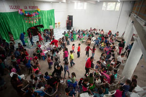 Overhead view of a celebration at a hope center as kids mingle and play in a large room decorated with balloons
