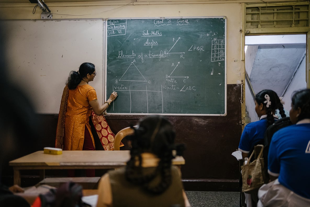 A teacher at a chalkboard teaching math in India