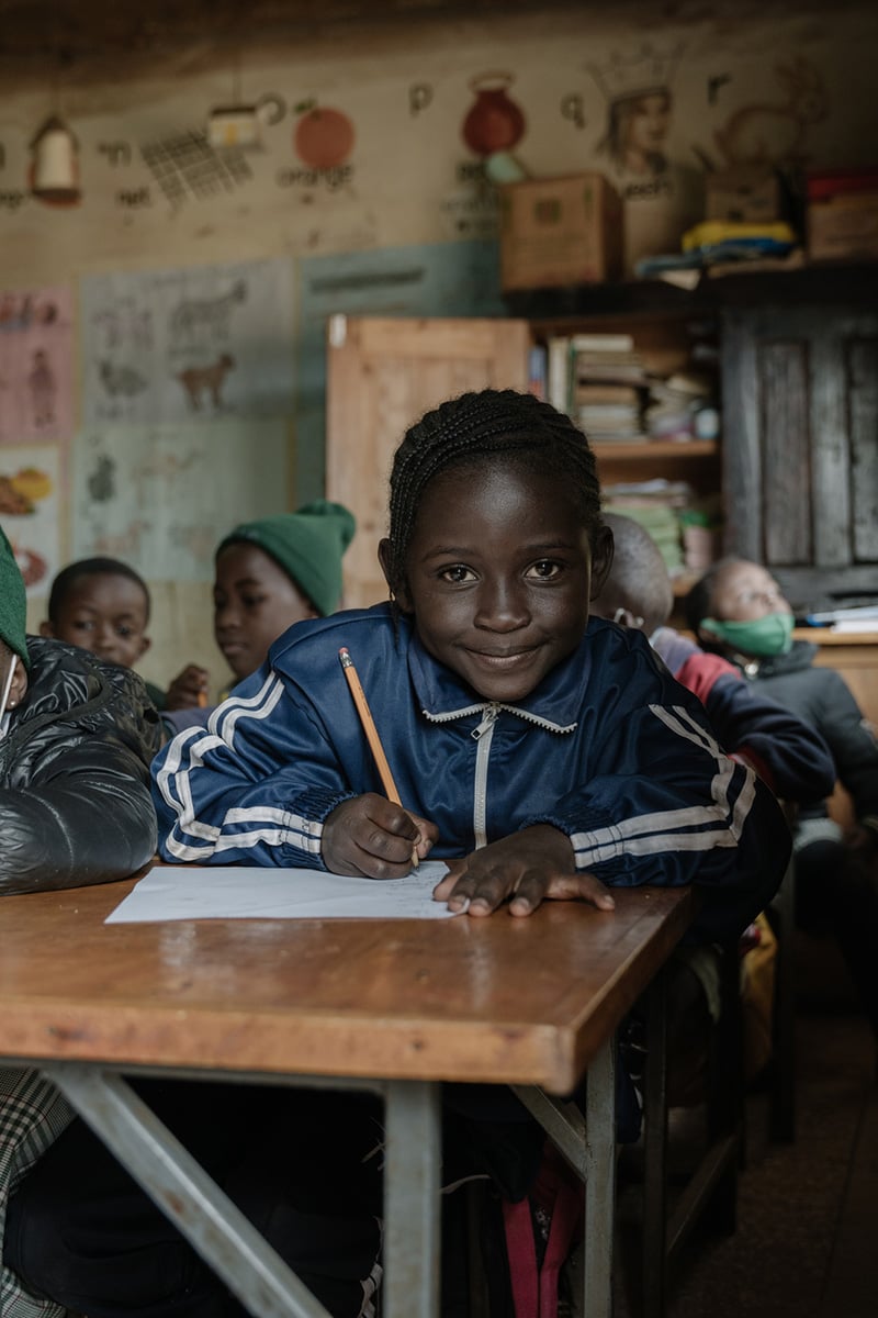A child sits writing at a desk in a classroom in Kenya 