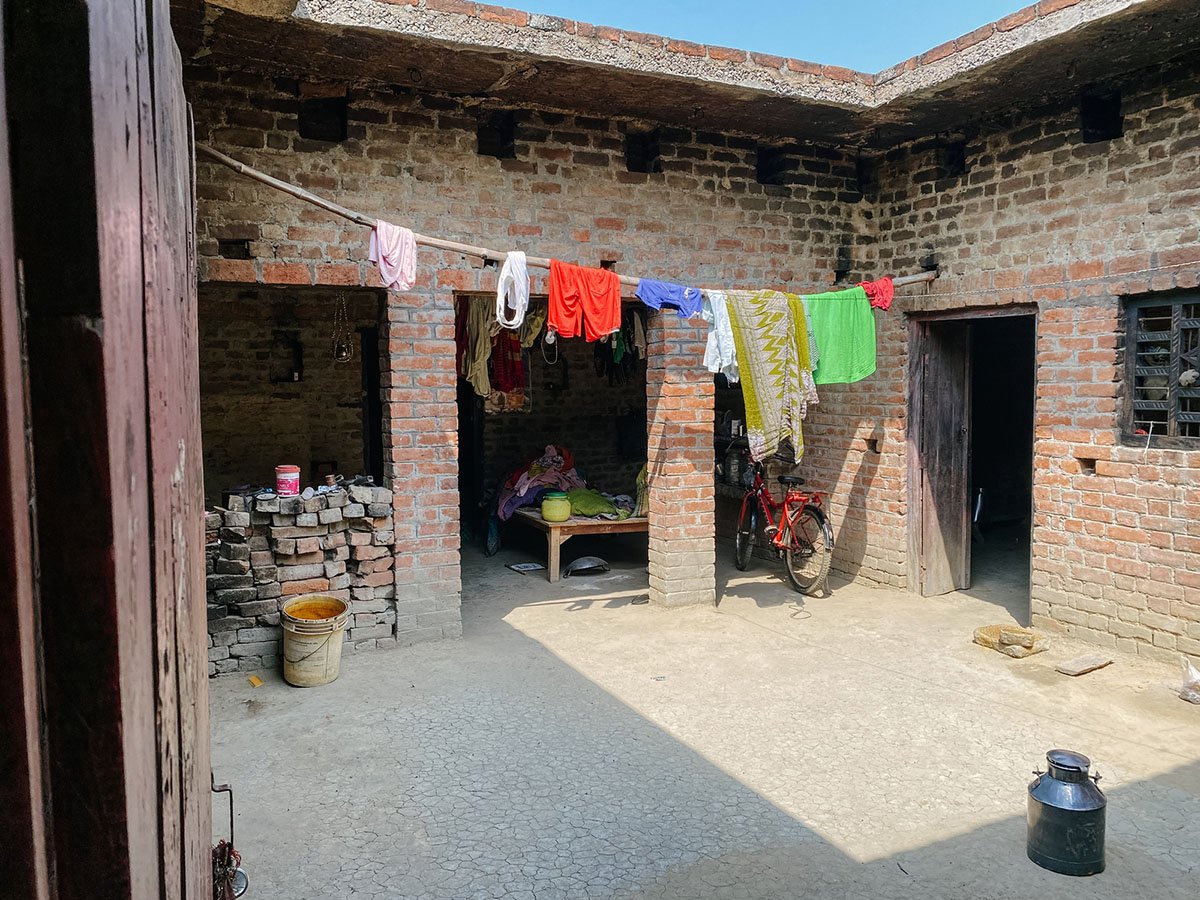 Laundry hangs in a packed-earth courtyard surrounded by a low brick building